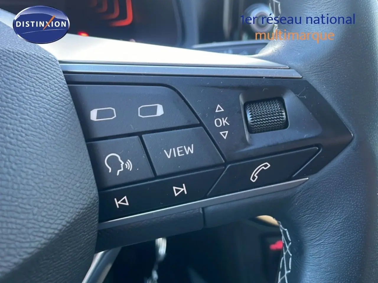 Gros plan sur les commandes multifonctions du volant cuir noir d’un SEAT Arona blanc 2025 avec toit gris.