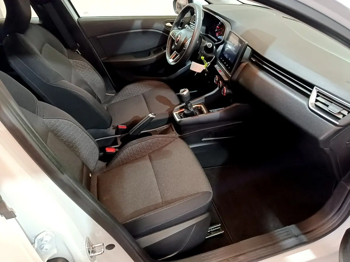 Intérieur avant droit de la Renault Clio Business blanche 2021, montrant sièges tissu et tableau de bord avec écran tactile.