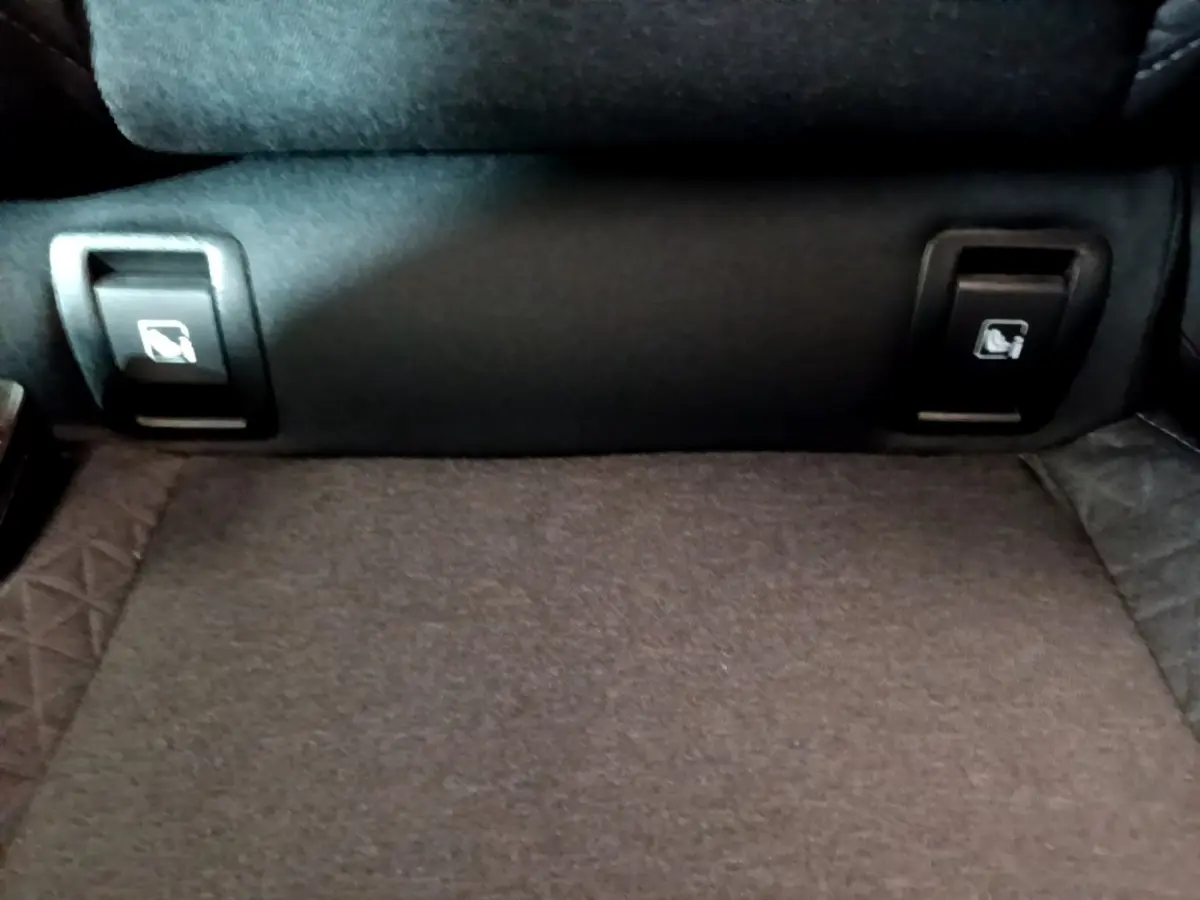 Gros plan sur les commandes de rabattement des sièges arrière dans l’habitacle noir de la Renault Clio Business blanche 2021.