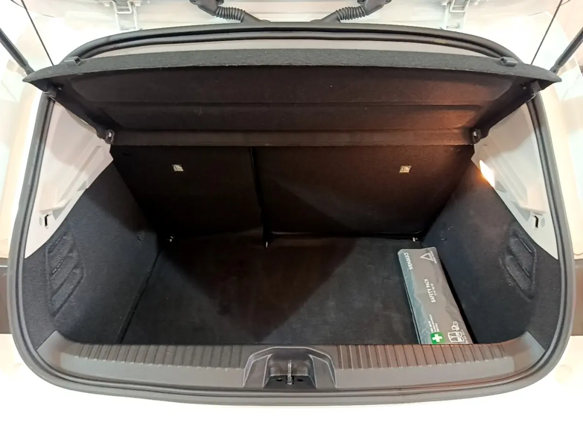 Coffre ouvert vu de l'arrière d'une Renault Clio blanche 2021, avec un kit de sécurité posé à droite.