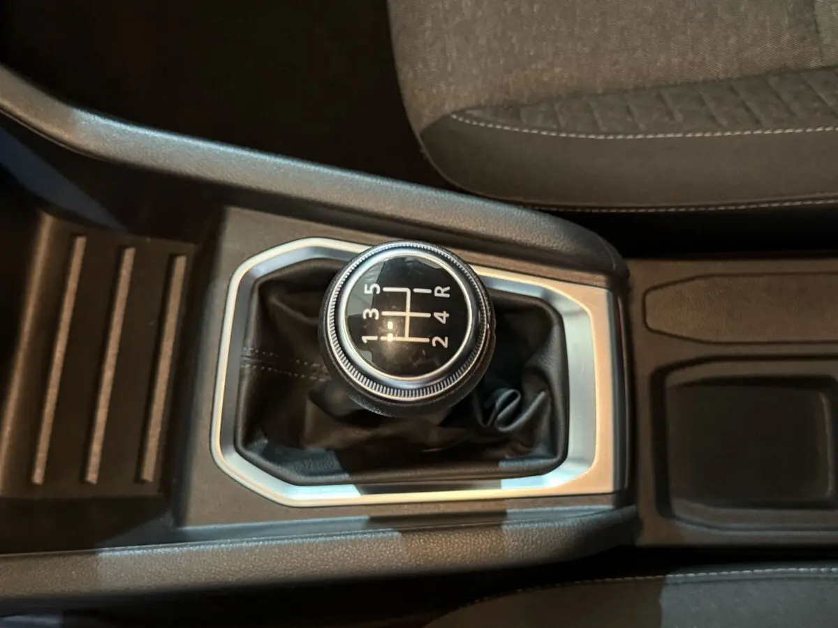 Gros plan sur le levier de vitesses manuel noir avec marquages blancs, entouré de garniture argentée dans l’habitacle.