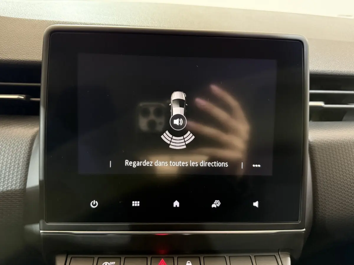 Écran tactile central de la Renault Clio Business blanc montrant l'alerte de détection de proximité au stationnement.