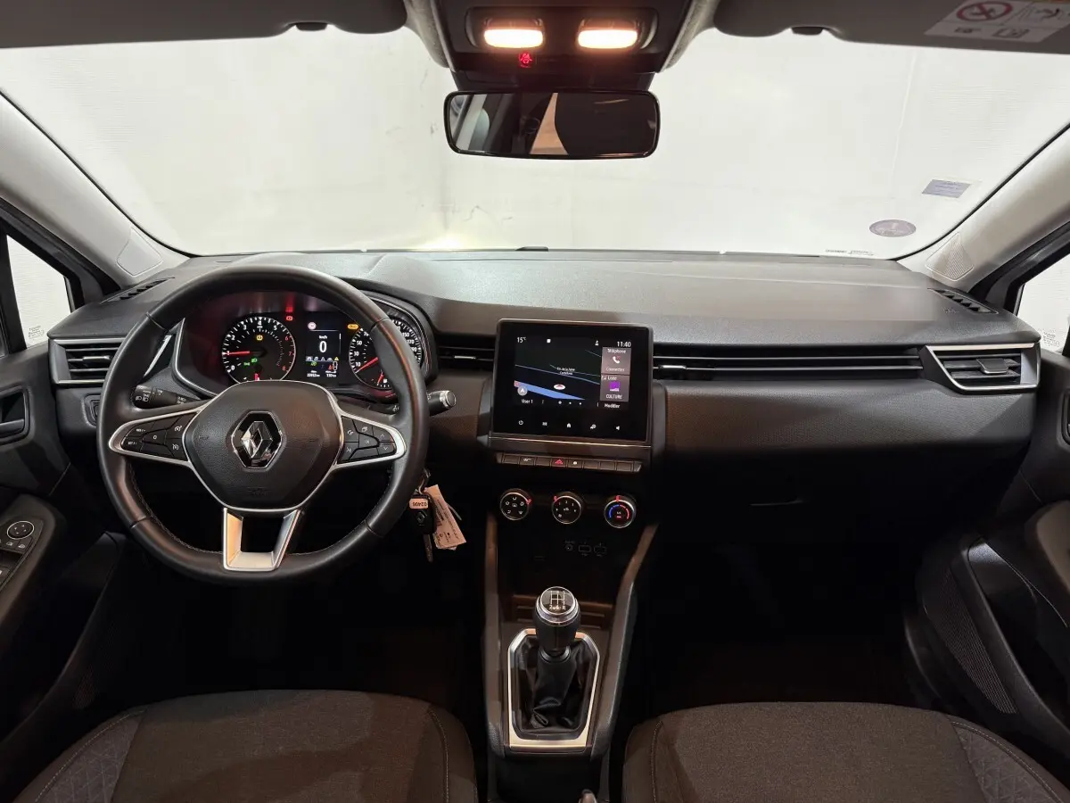 Vue intérieure avant de la Renault Clio Business avec tableau de bord noir, écran tactile central et volant multifonctions cuir.
