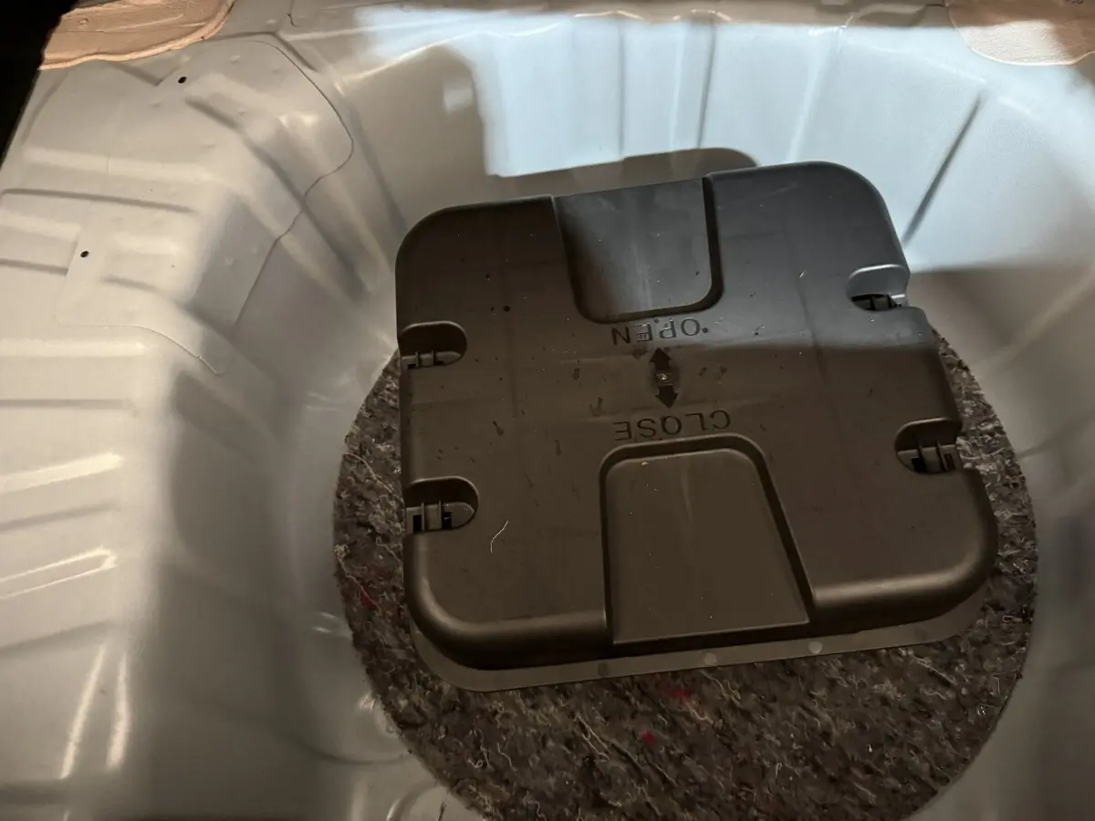 Gros plan sur le coffre blanc d’une Renault Clio 2020, montrant la roue de secours et son boîtier noir central.