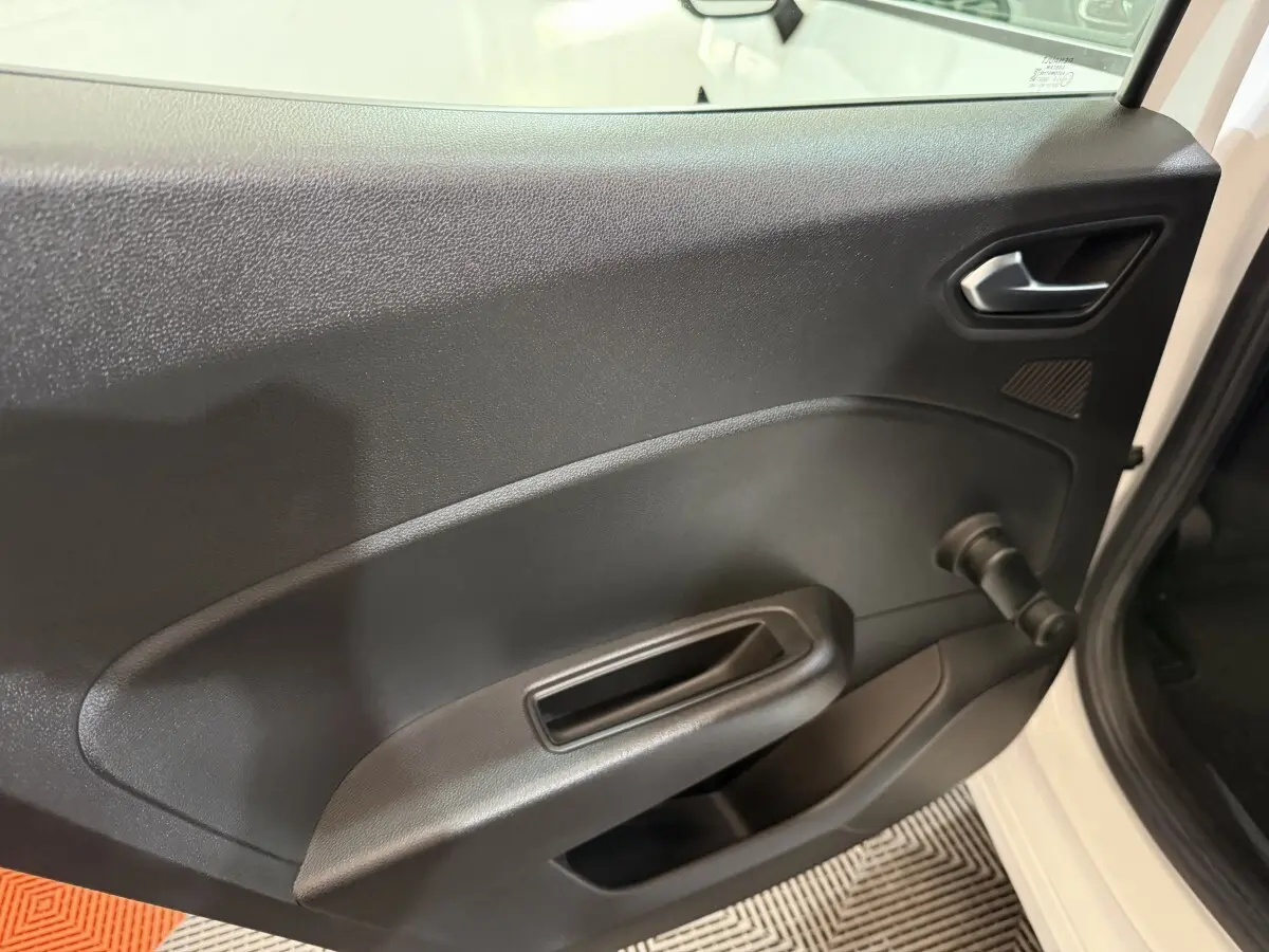 Vue rapprochée de la porte intérieure côté droit d’une Renault Clio Business blanche, avec poignée et manivelle de vitre.