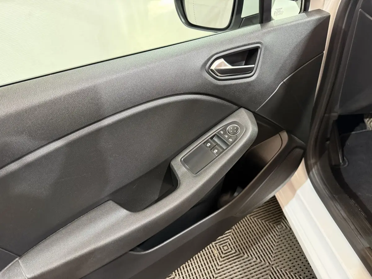 Intérieur côté conducteur de Renault Clio Business blanc, montrant la porte avec commandes des vitres et poignée noire.