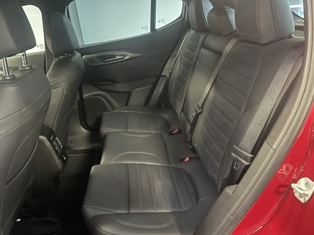 Vue intérieure côté droit des sièges arrière en cuir noir de l'Alfa Romeo Tonale rouge 2024, avec ceinture de sécurité visible.