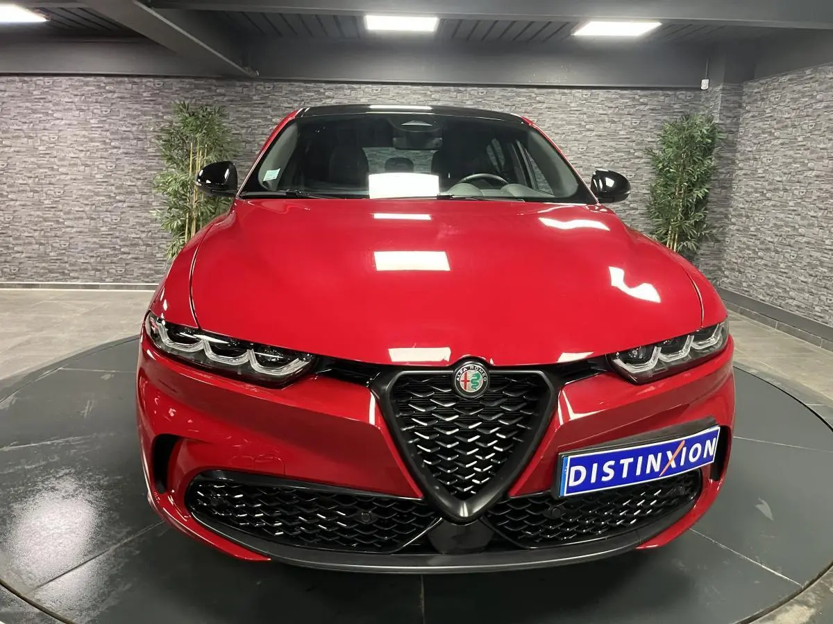 Vue frontale d'une Alfa Romeo Tonale rouge avec calandre noire et logo Alfa Romeo au centre.