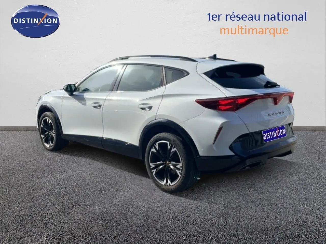 Vue 3/4 arrière droite d’un CUPRA Formentor blanc neige métal avec jantes noires bicolores et toit noir.