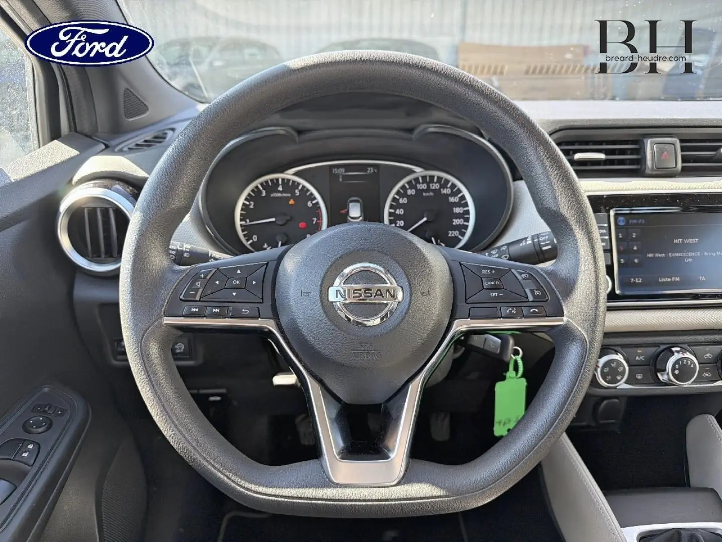 Vue intérieure centrée sur le volant Nissan Micra 2017, tableau de bord et écran tactile visibles en arrière-plan.