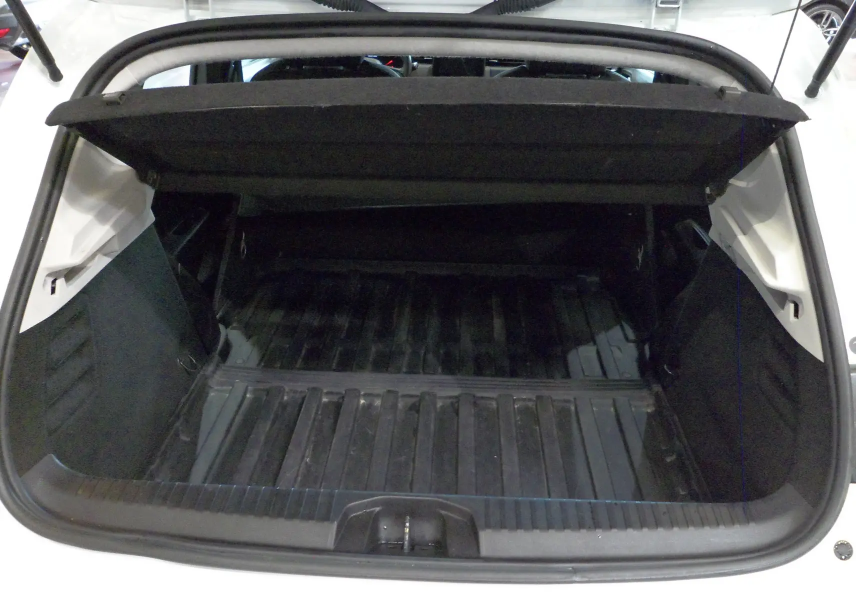 Coffre ouvert vu de l'arrière d'une Renault Clio V blanche Glacier, montrant l'espace de chargement vide.