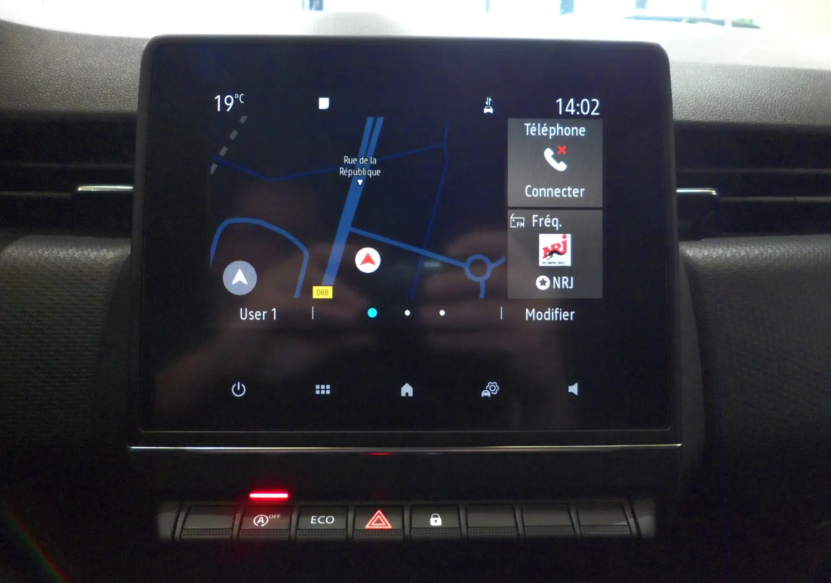 Écran tactile central du tableau de bord de la Renault Clio V blanc glacier, affichant la navigation et les options multimédia.