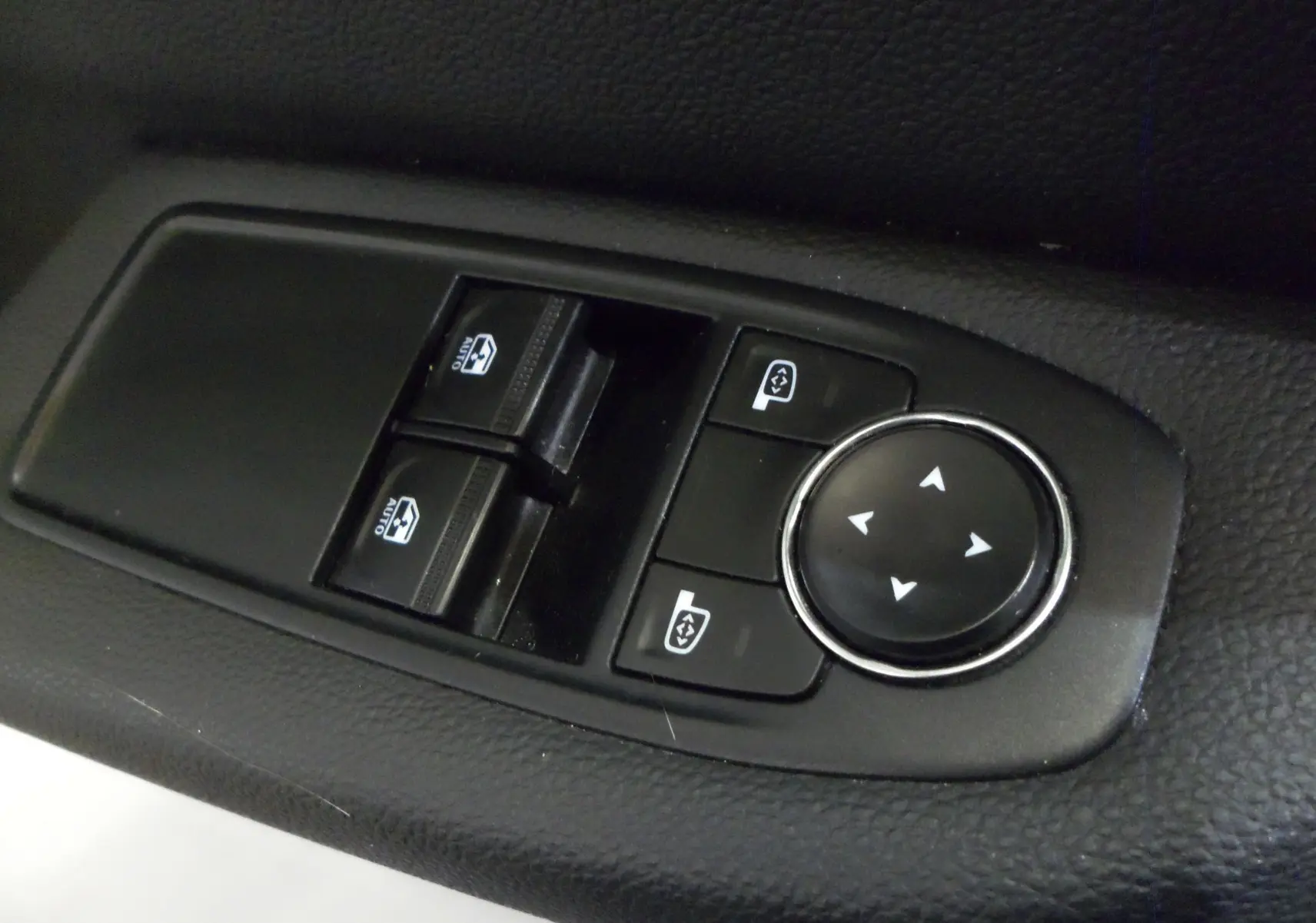 Commande des vitres électriques et réglage des rétroviseurs sur la porte côté conducteur d'une Renault Clio V blanche.