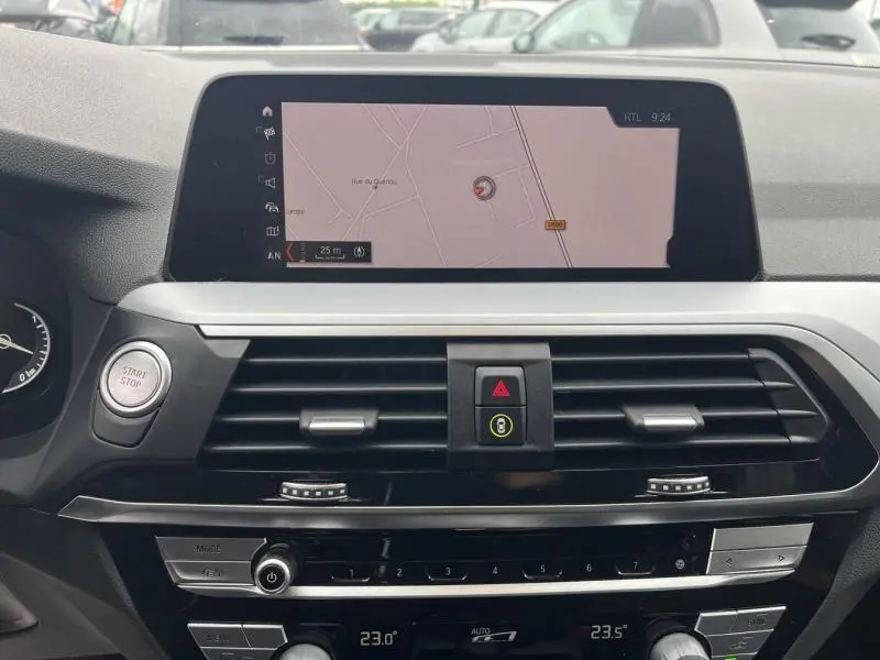 Vue rapprochée de l'écran tactile central et de la console de bord noire du BMW X3 xDrive30eA 2020 avec navigation affichée.