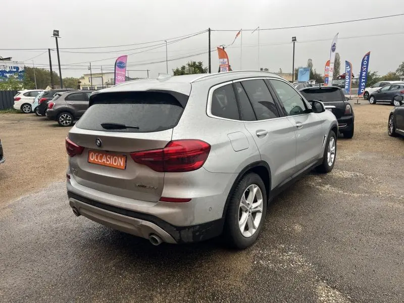 BMW X3 xDrive30e hybride rechargeable en Glacier Silver, vue 3/4 arrière droit avec feux LED et double sortie d'échappement chromée.