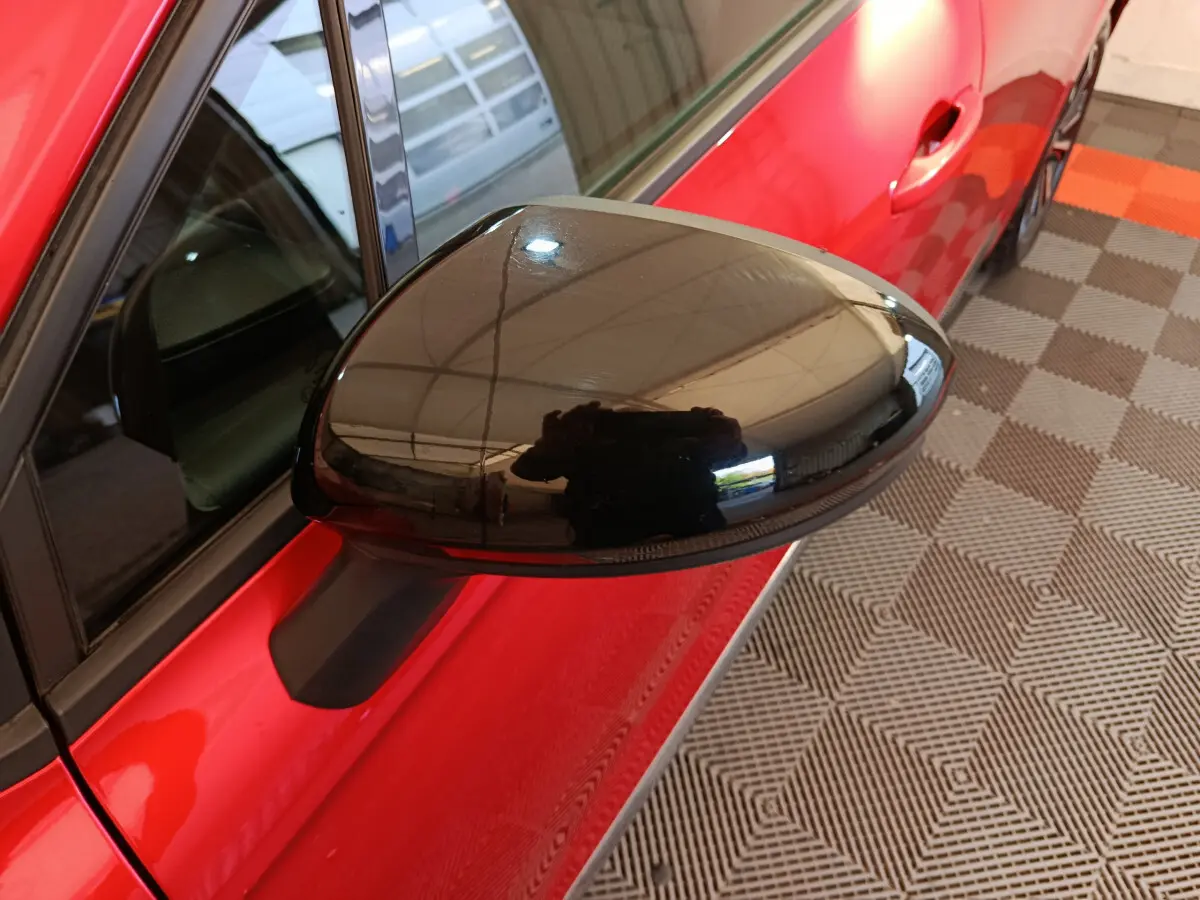 Rétroviseur noir côté gauche d’une Renault Clio Techno TCe 90 rouge 2024, vue rapprochée en intérieur.