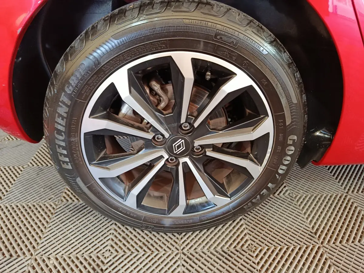 Gros plan sur la roue avant droite d’une Renault Clio rouge 2024 avec jante alliage noire et argentée.