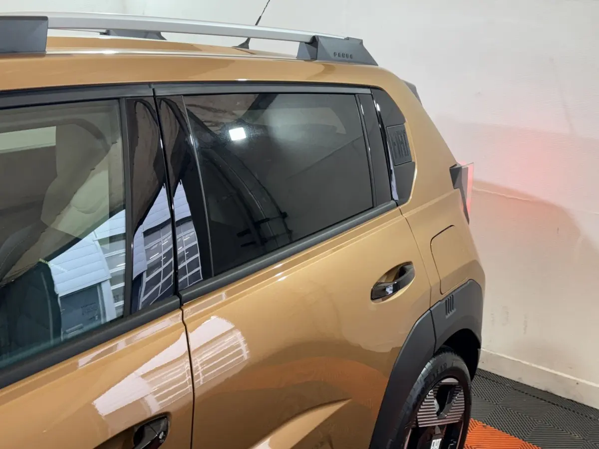 Vue latérale arrière droite d'une FIAT Grande Panda marron 2025 avec vitres teintées et barres de toit chromées.