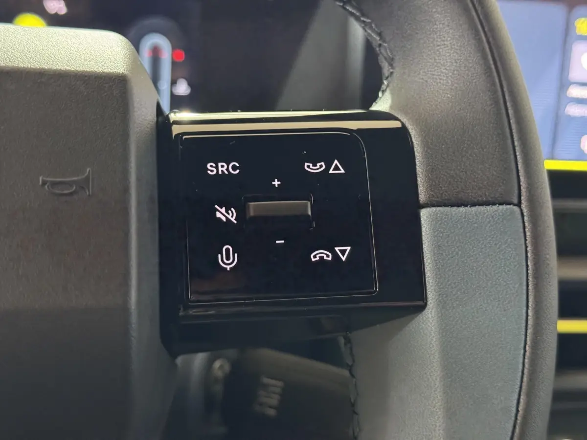 Gros plan sur les commandes gauche du volant cuir de la Fiat Grande Panda 2025, boutons multifonctions noirs.