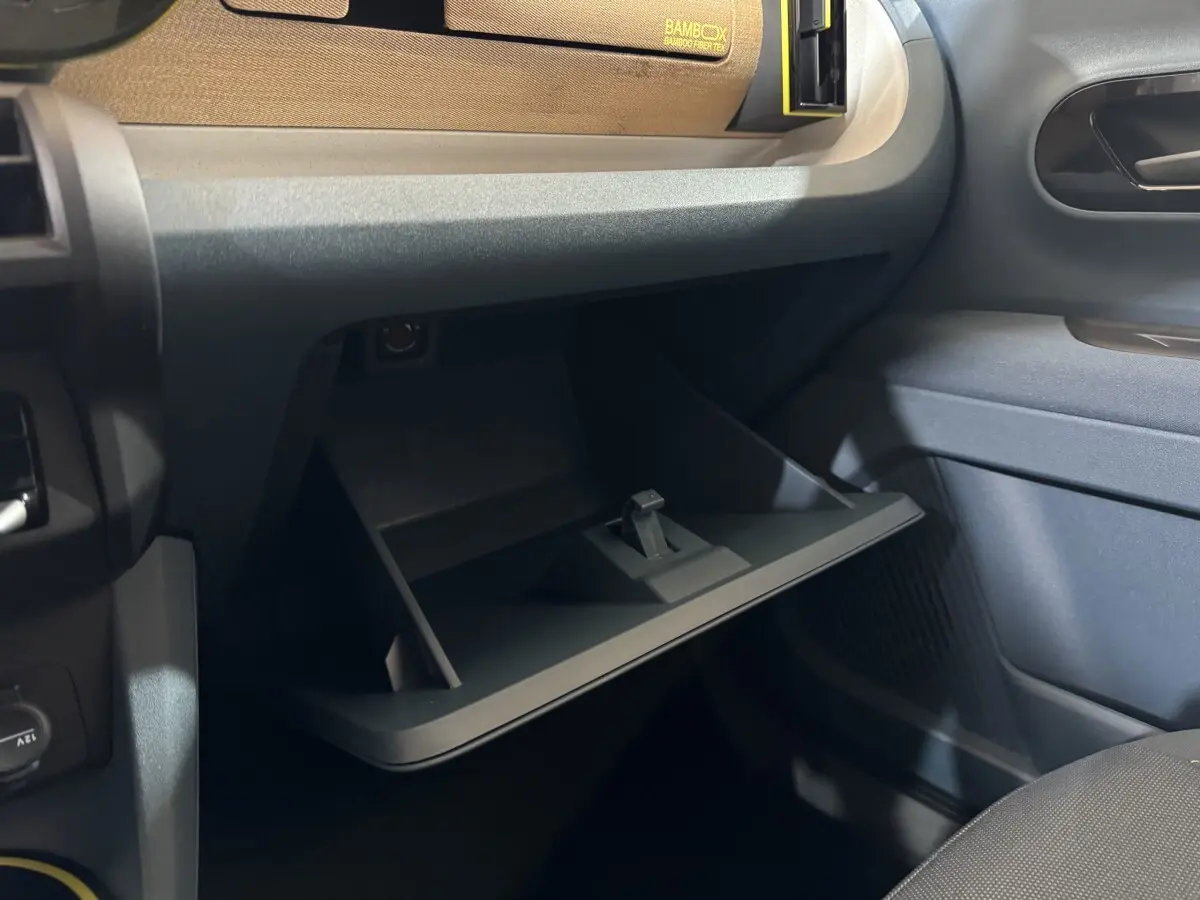 Gros plan sur la boîte à gants ouverte côté passager de la Fiat Grande Panda marron, intérieur sombre et moderne.