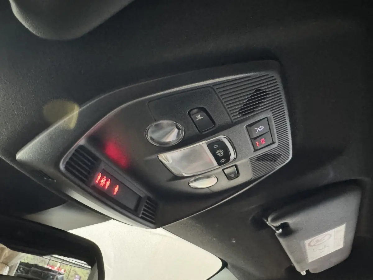 Vue intérieure en plongée du plafonnier noir avec commandes d’éclairage et affichage rouge de la FIAT Grande Panda marron.