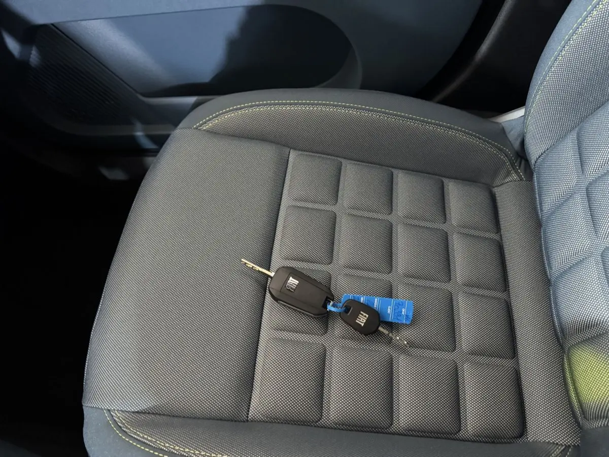 Gros plan sur la clé FIAT posée sur le siège avant gris à surpiqûres jaunes de la Grande Panda 2025.