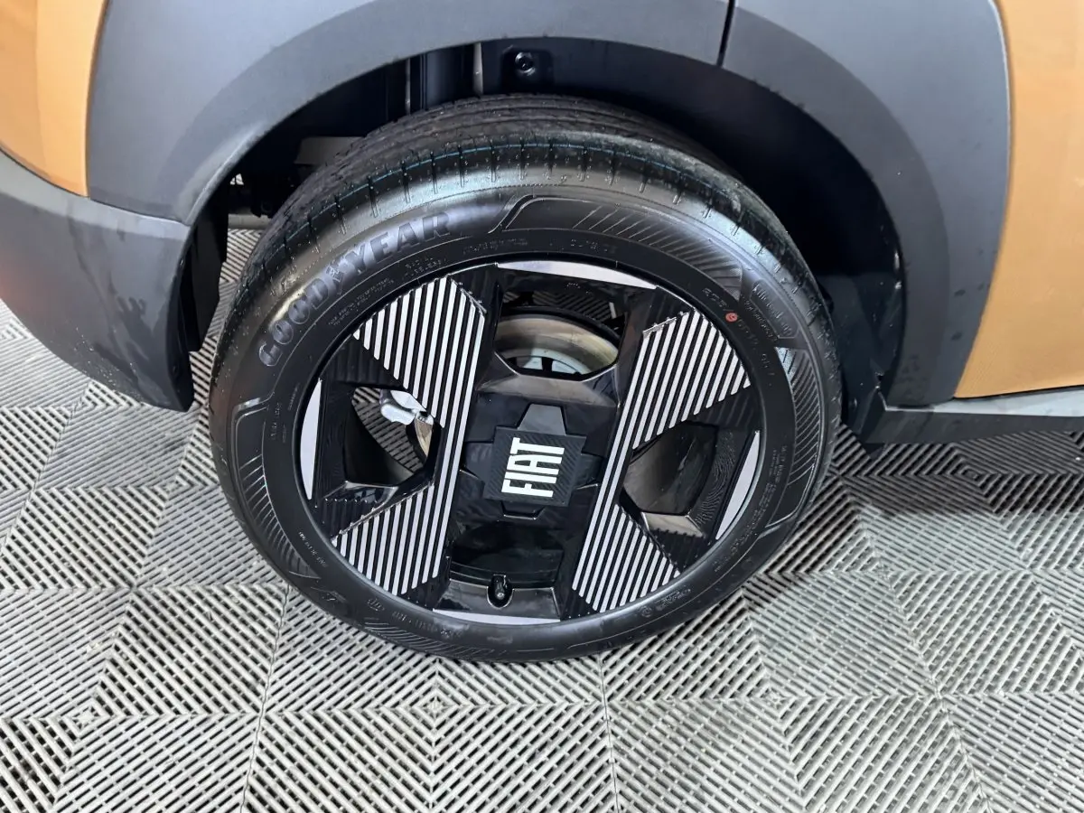 Gros plan sur la roue avant gauche marron de la Fiat Grande Panda 1.2 Hybrid avec jante noire et motifs rayés blancs.