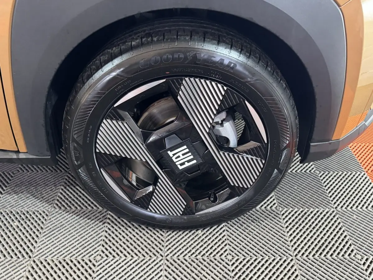 Gros plan sur la roue avant droite marron de la FIAT Grande Panda 1.2 Hybrid avec jante noire et motifs rayés.