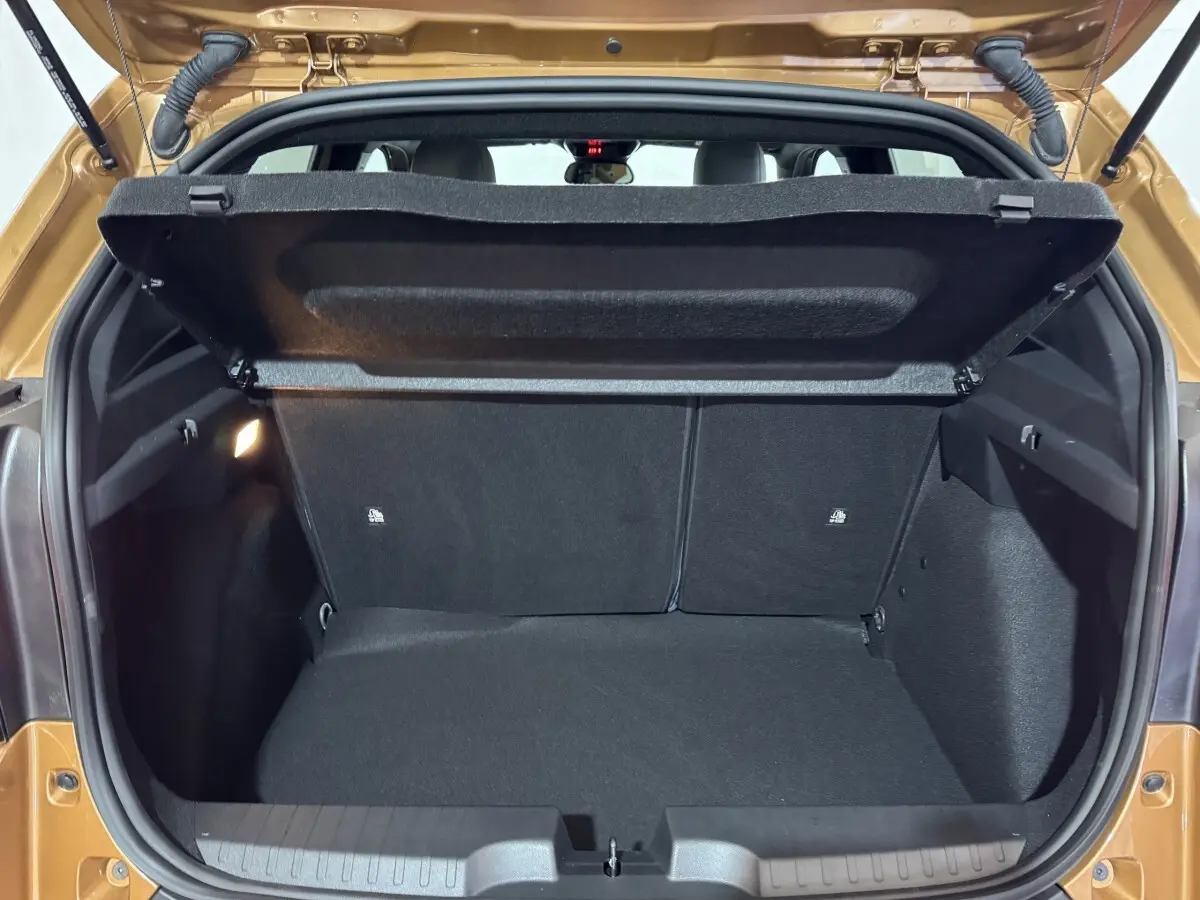 Coffre ouvert vu de l'arrière d'une FIAT Grande Panda marron 2025, intérieur noir et banquette arrière visible.