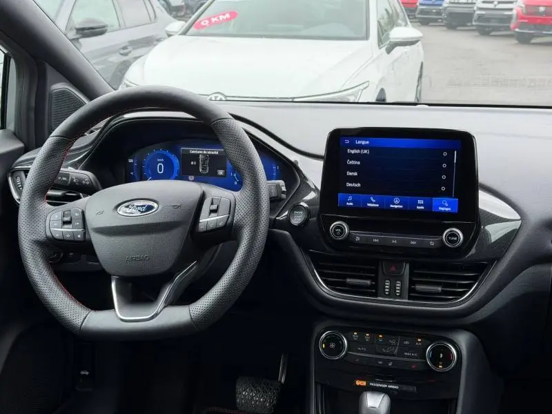 Vue intérieure du tableau de bord et volant noir perforé du Ford Puma 2024 avec écran tactile et commandes multifonctions.