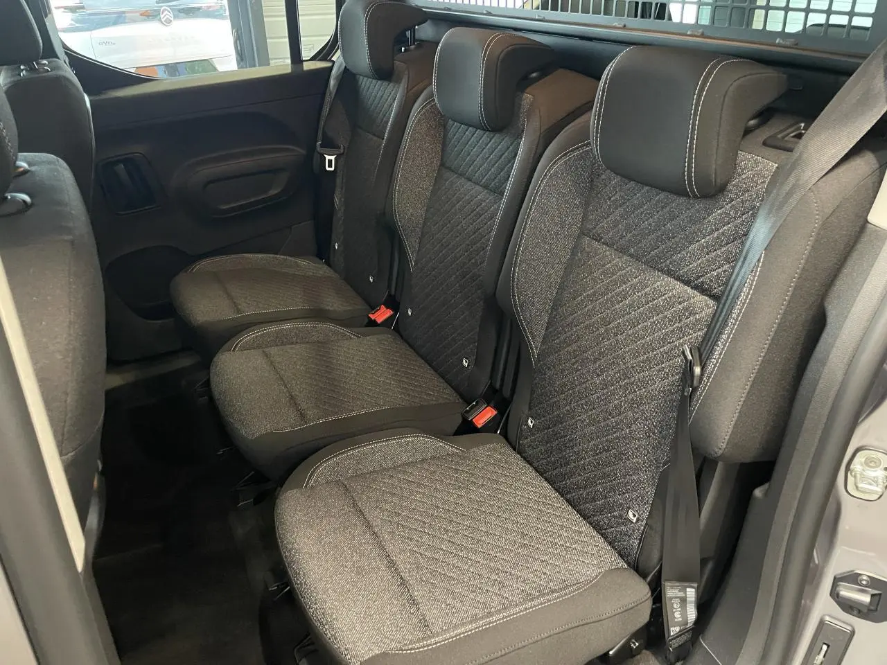 Vue intérieure des sièges arrière en tissu gris du Peugeot Rifter 2026, avec portes latérales coulissantes ouvertes.