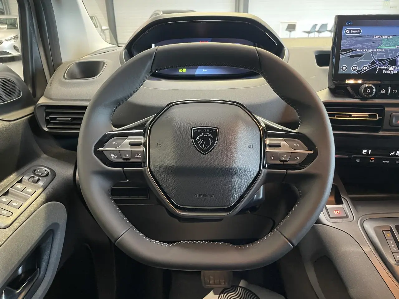 Vue rapprochée du volant cuir multifonction noir du Peugeot Rifter 2026 avec tableau de bord numérique et écran tactile.