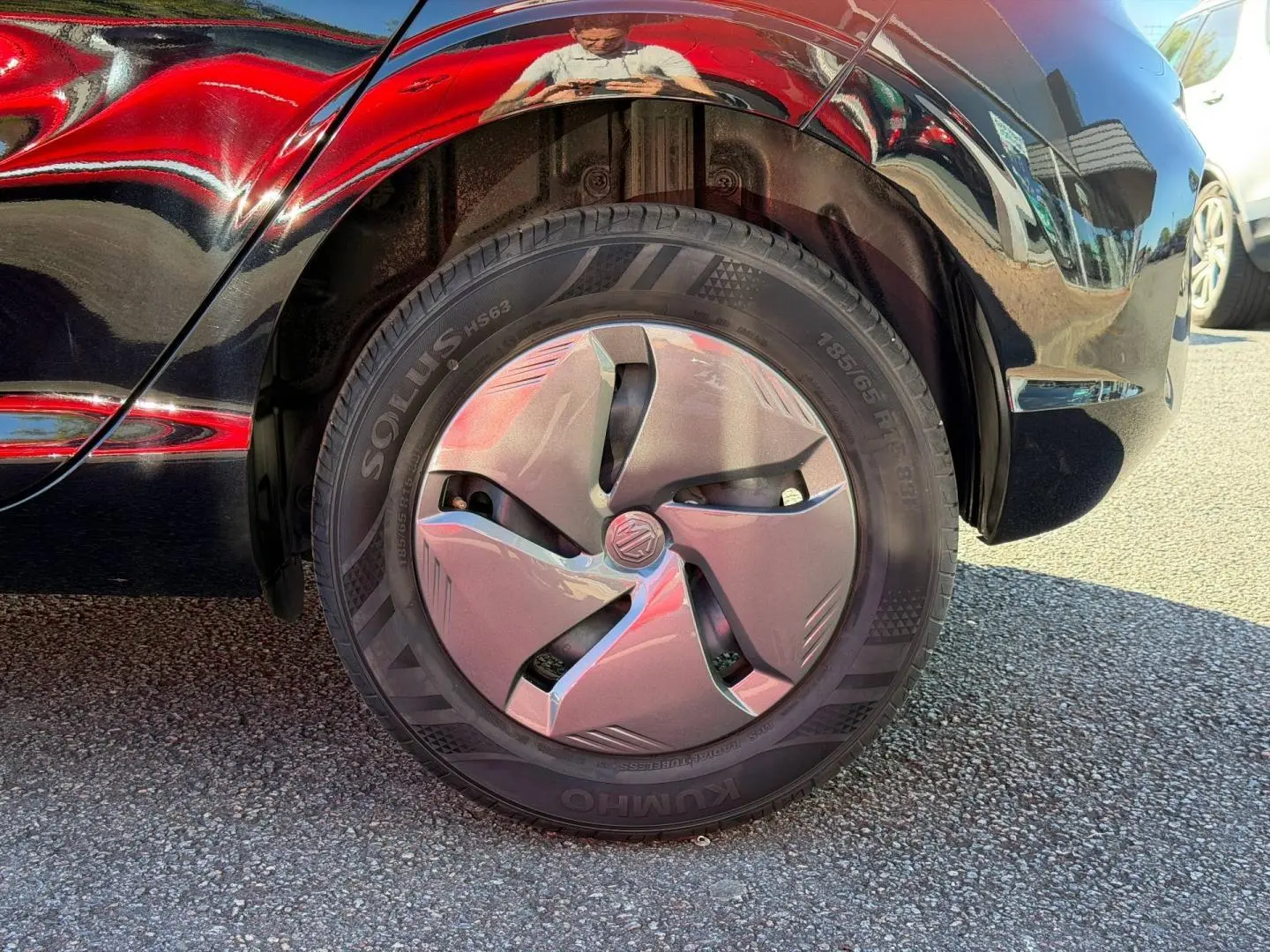 Gros plan sur la roue arrière droite d’une MG3 1.5 Hybrid+ 2024 en Pebble Black métallisé avec enjoliveur gris.