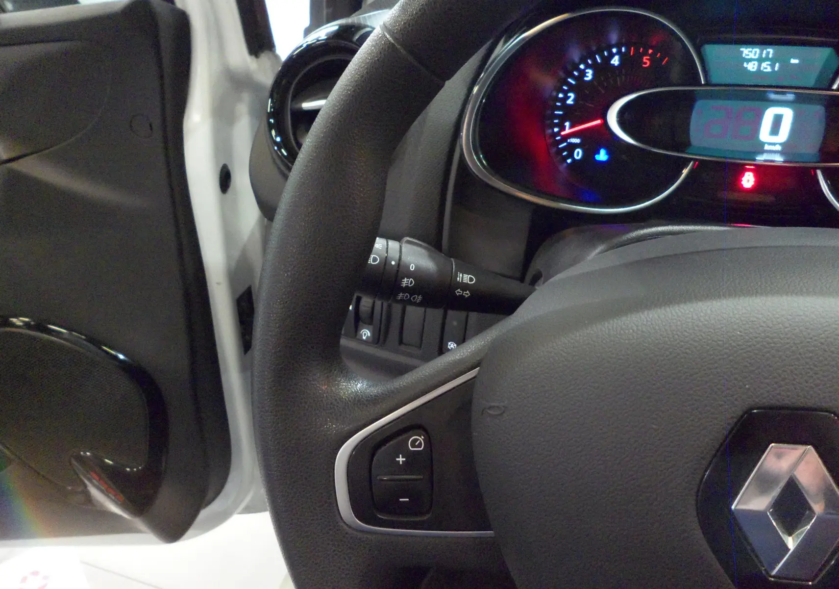Vue rapprochée du volant et du tableau de bord d'une Renault Clio IV Société blanc glacier, avec affichage numérique du compteur.