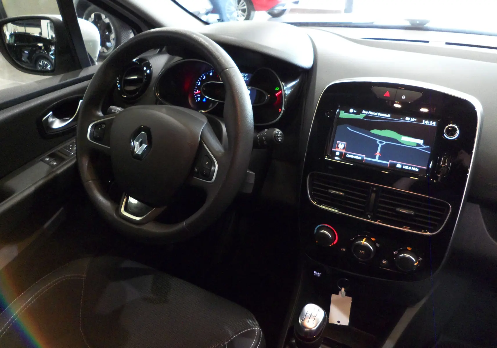 Intérieur de la Renault Clio IV Société 2019 vu côté conducteur, avec volant, tableau de bord et écran tactile GPS allumé.