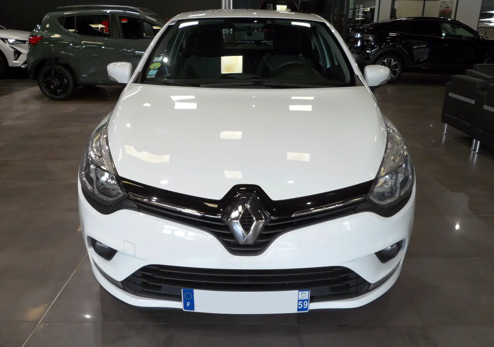 Vue avant d'une Renault Clio IV Société blanche Glacier avec calandre noire et logo Renault bien visible.