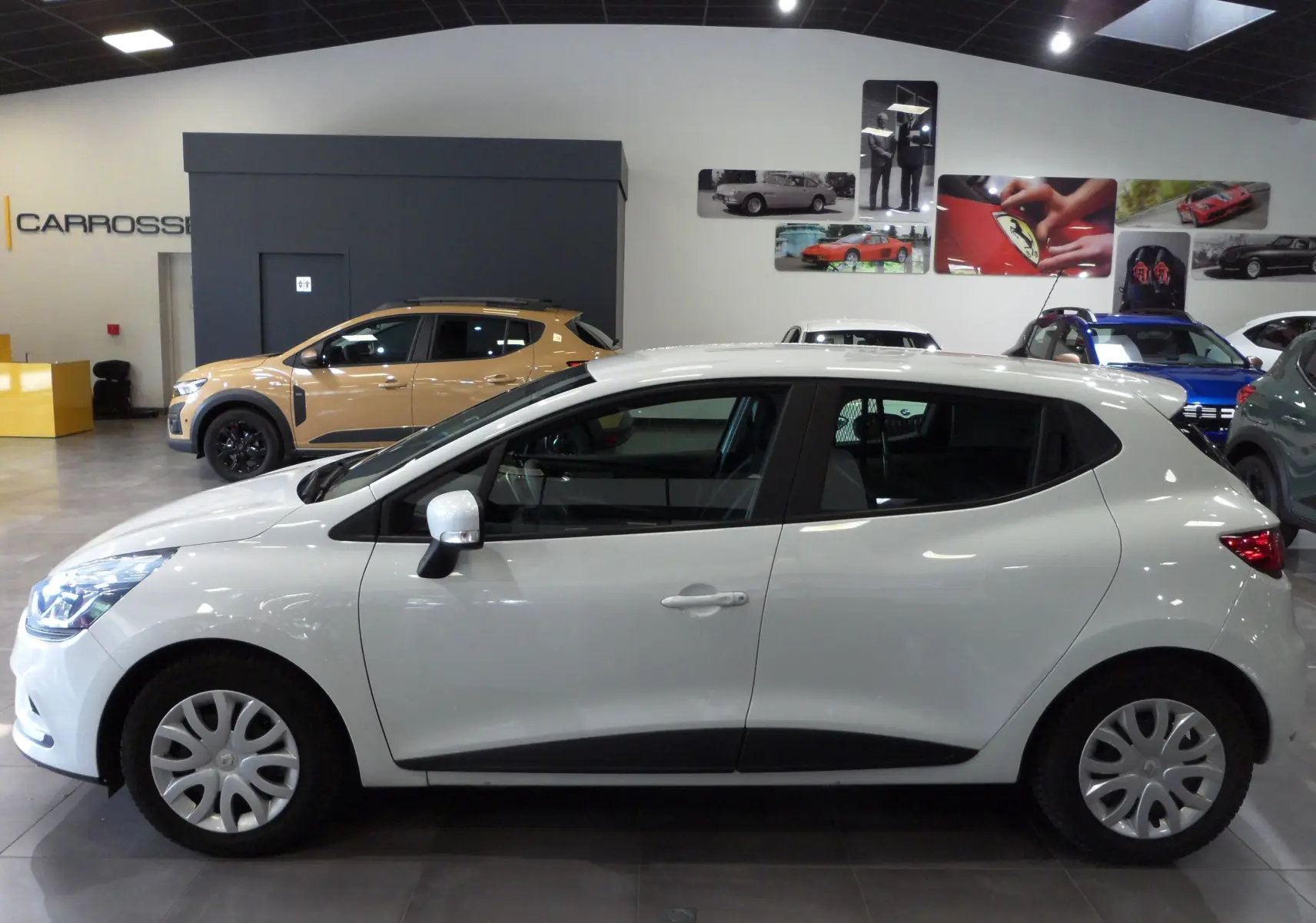 Profil côté gauche d'une Renault Clio IV Société blanc glacier, avec jantes tôles et poignées de porte assorties.