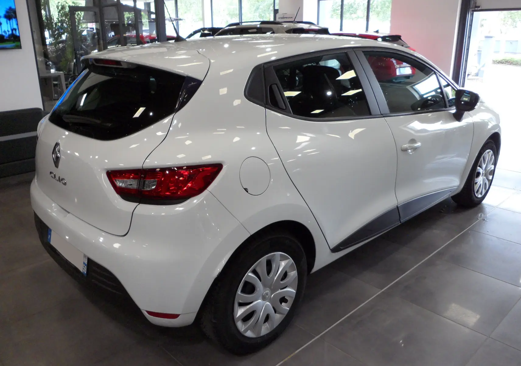 Renault Clio IV Société blanc glacier vue 3/4 arrière droit en intérieur avec jantes tôles et vitres teintées.