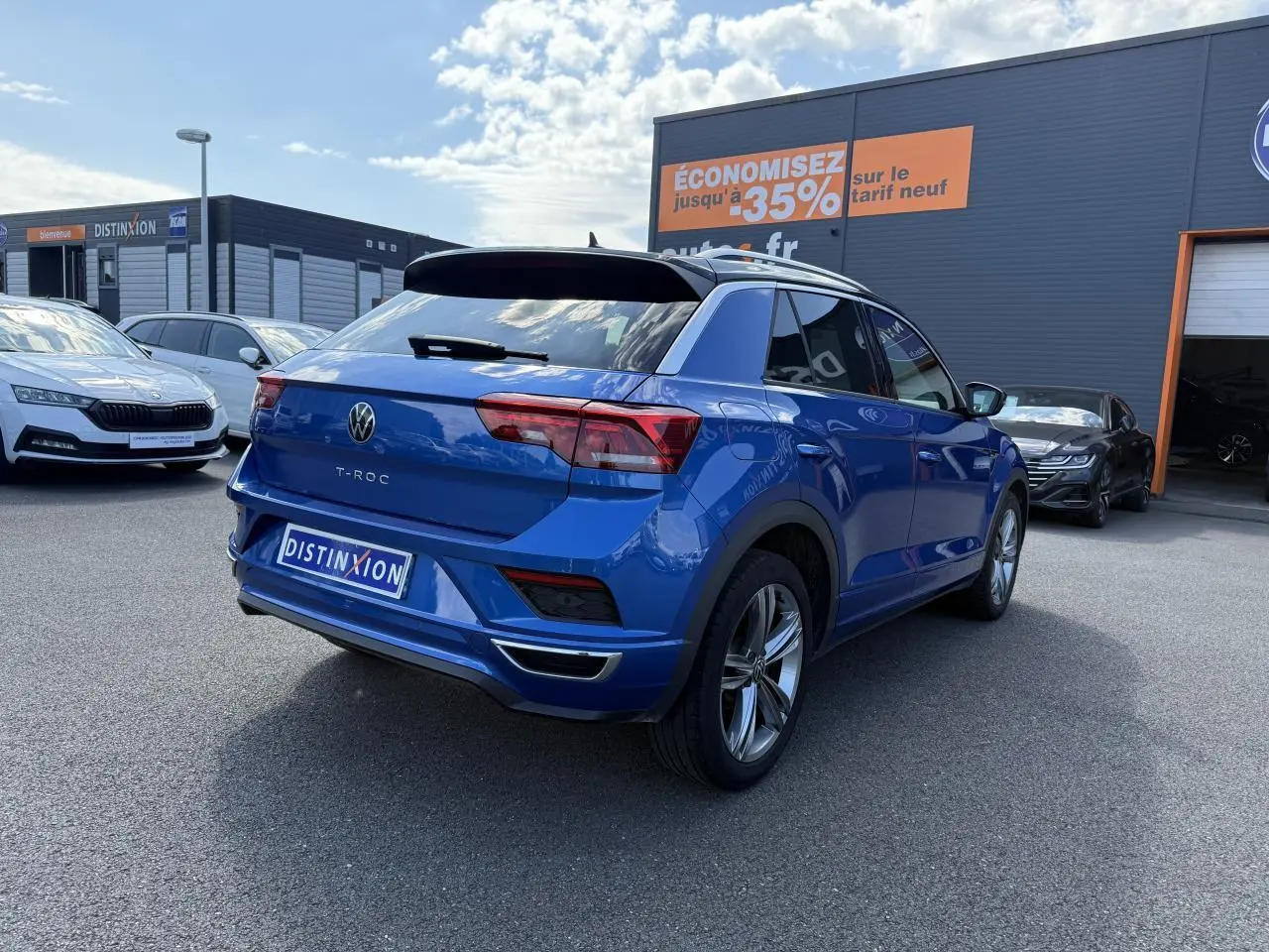 Volkswagen T-Roc bleu Ravenna métallisé vu en 3/4 arrière droit avec jantes alliage et toit noir.