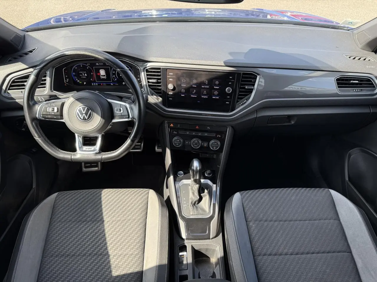 Vue intérieure avant du Volkswagen T-Roc 2022 avec tableau de bord numérique, volant cuir multifonction et console centrale moderne.