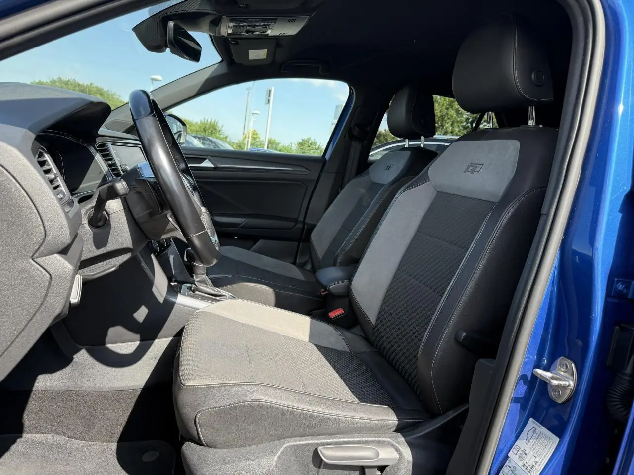 Intérieur avant du Volkswagen T-Roc bleu Ravenna, sièges sport R-Line en cuir et alcantara gris et noir.
