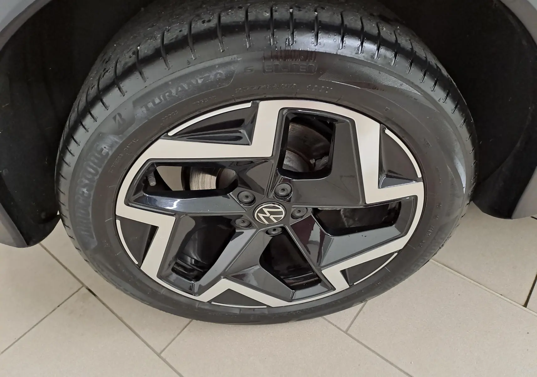 Gros plan sur la jante noire et argentée du Volkswagen Tiguan 2025, mettant en valeur le logo VW central.