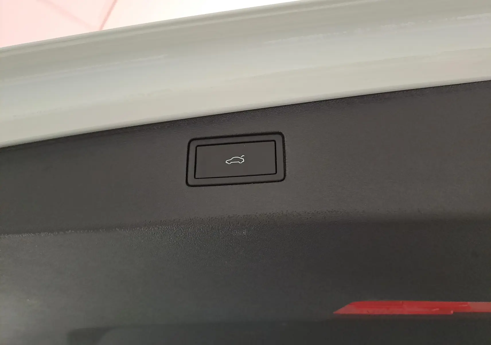 Bouton d'ouverture électrique du coffre sur la partie intérieure du hayon d'un Volkswagen Tiguan blanc pur.