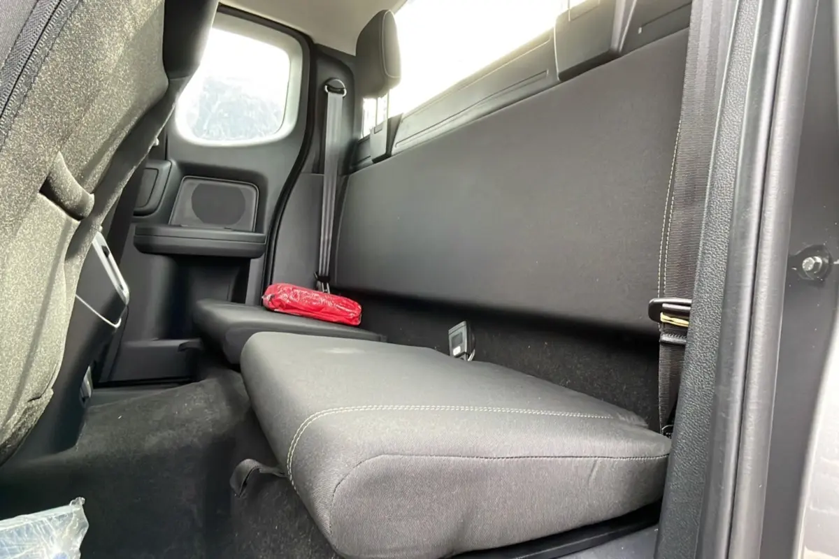Vue intérieure arrière côté droit du Ford Ranger gris carbone, banquette simple avec ceinture et trousse de secours rouge.