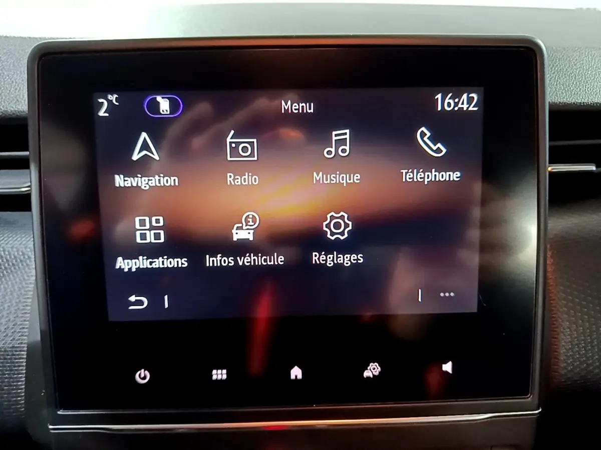 Écran tactile central de la Renault Clio Business bleu affichant le menu principal avec navigation et radio.