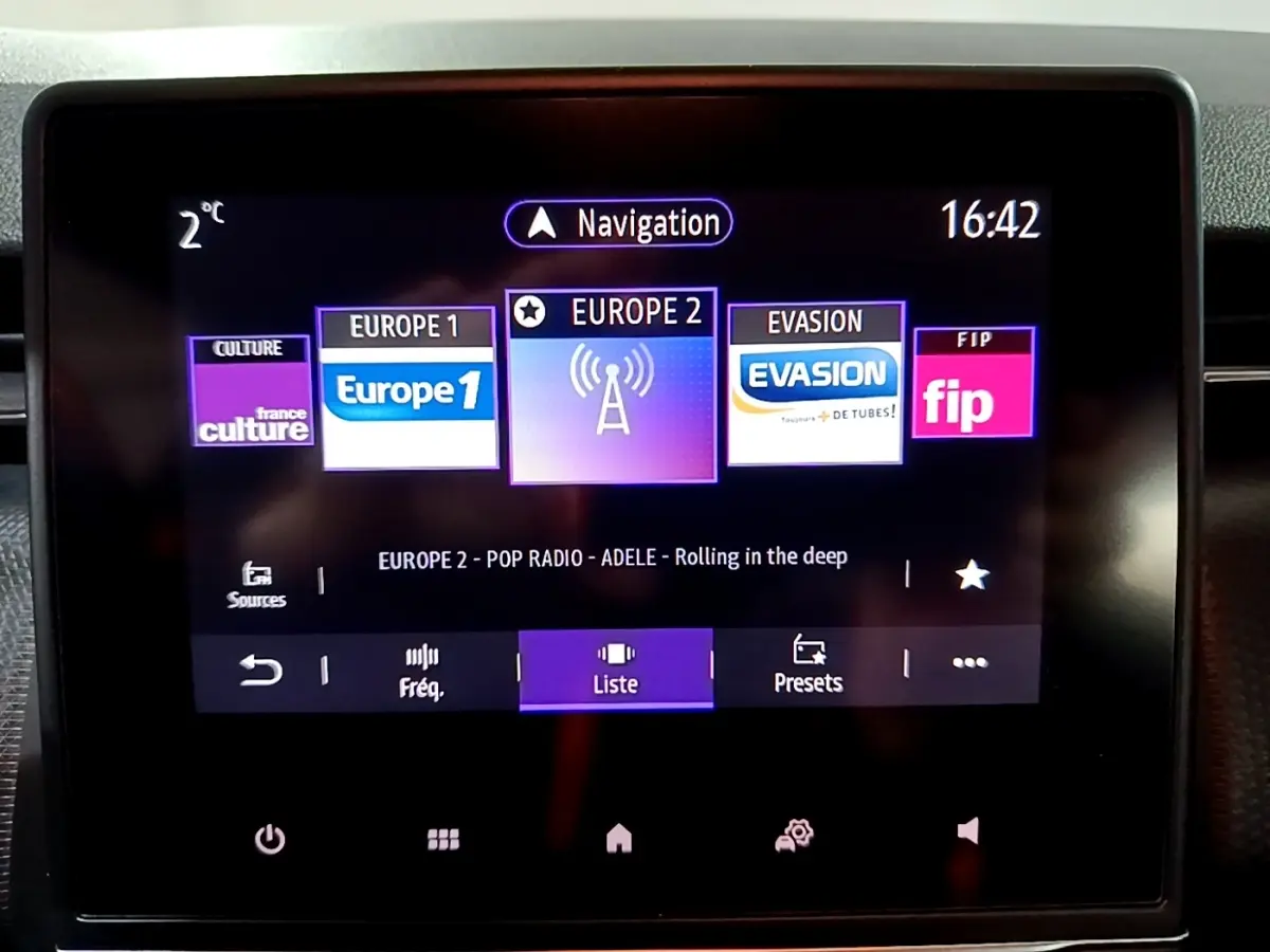 Écran tactile central du tableau de bord de la Renault Clio Business bleu, affichant les stations radio et la navigation.