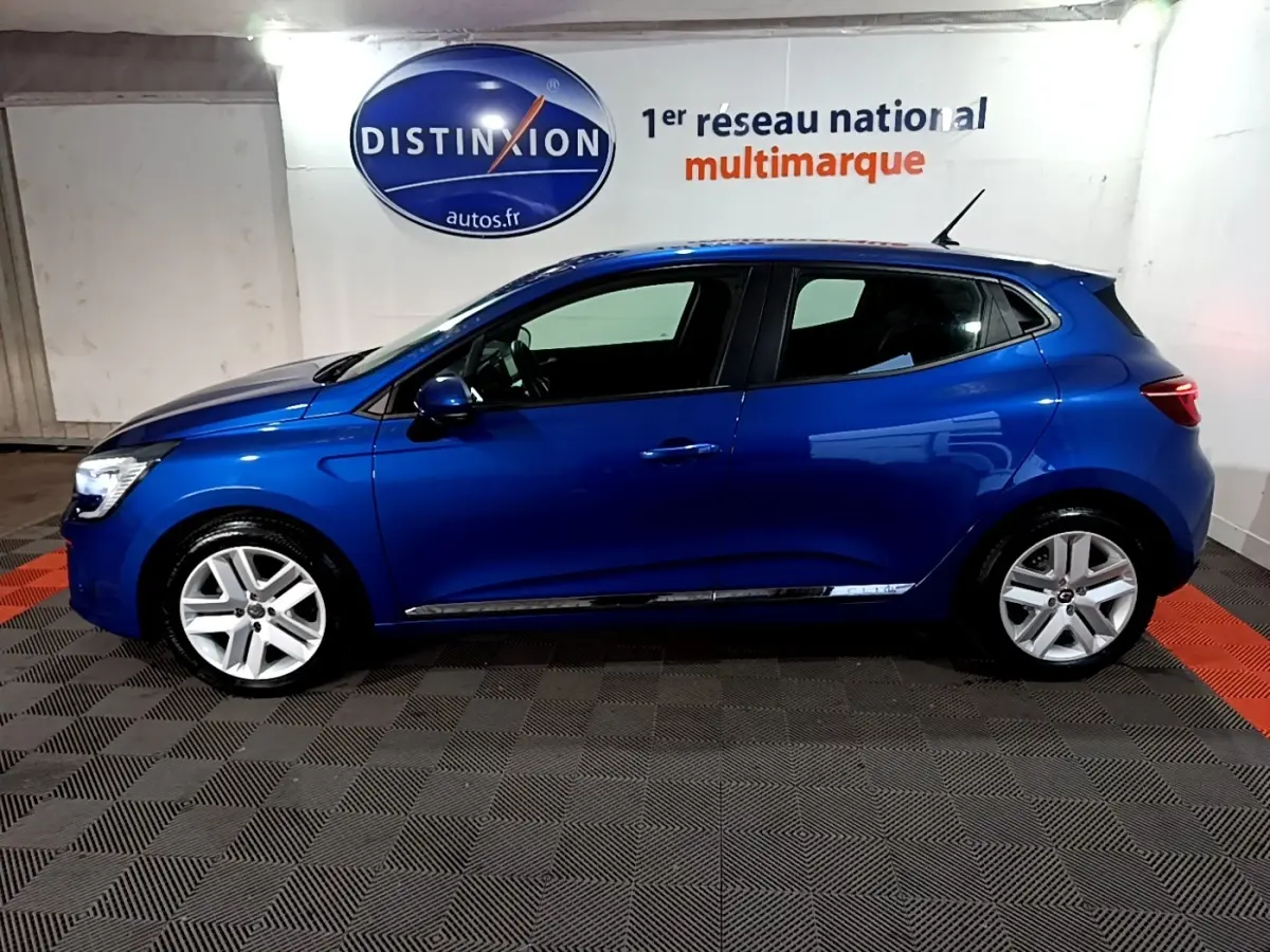 Profil droit d'une Renault Clio Business bleu vif, avec jantes alliage et rétroviseurs assortis, en intérieur showroom.
