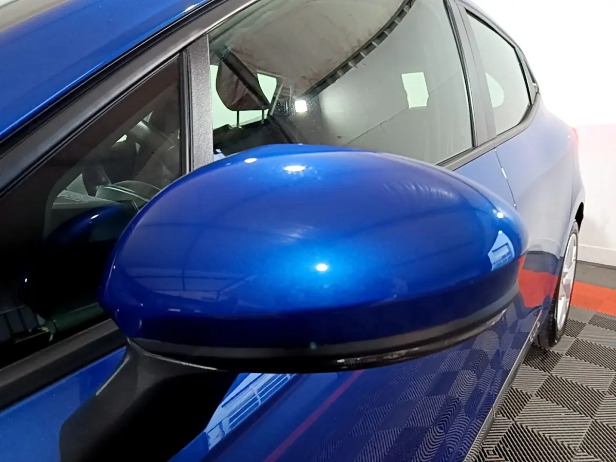 Rétroviseur bleu en gros plan côté gauche sur Renault Clio Business 2022, vue latérale partielle du véhicule.