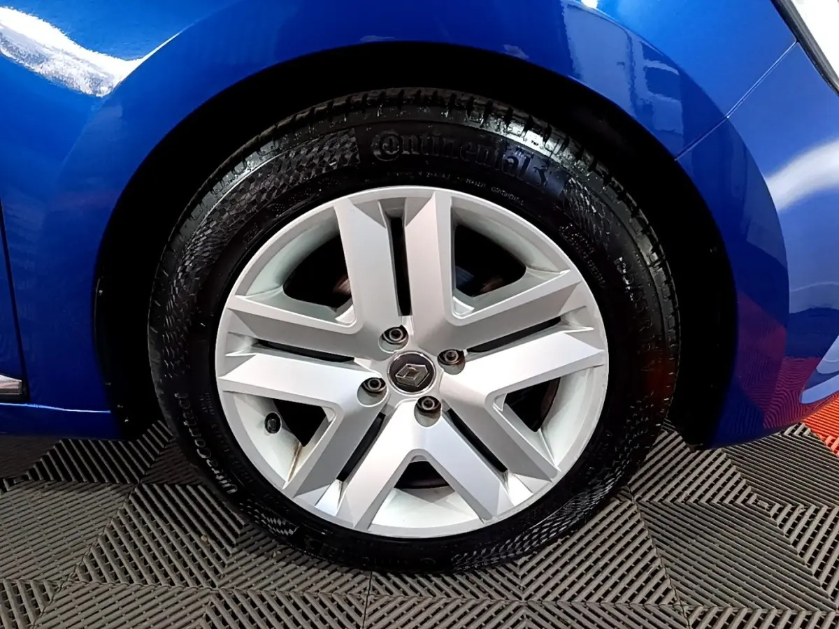 Gros plan sur la roue avant droite d'une Renault Clio Business bleu, avec jante alliage et logo Renault central.