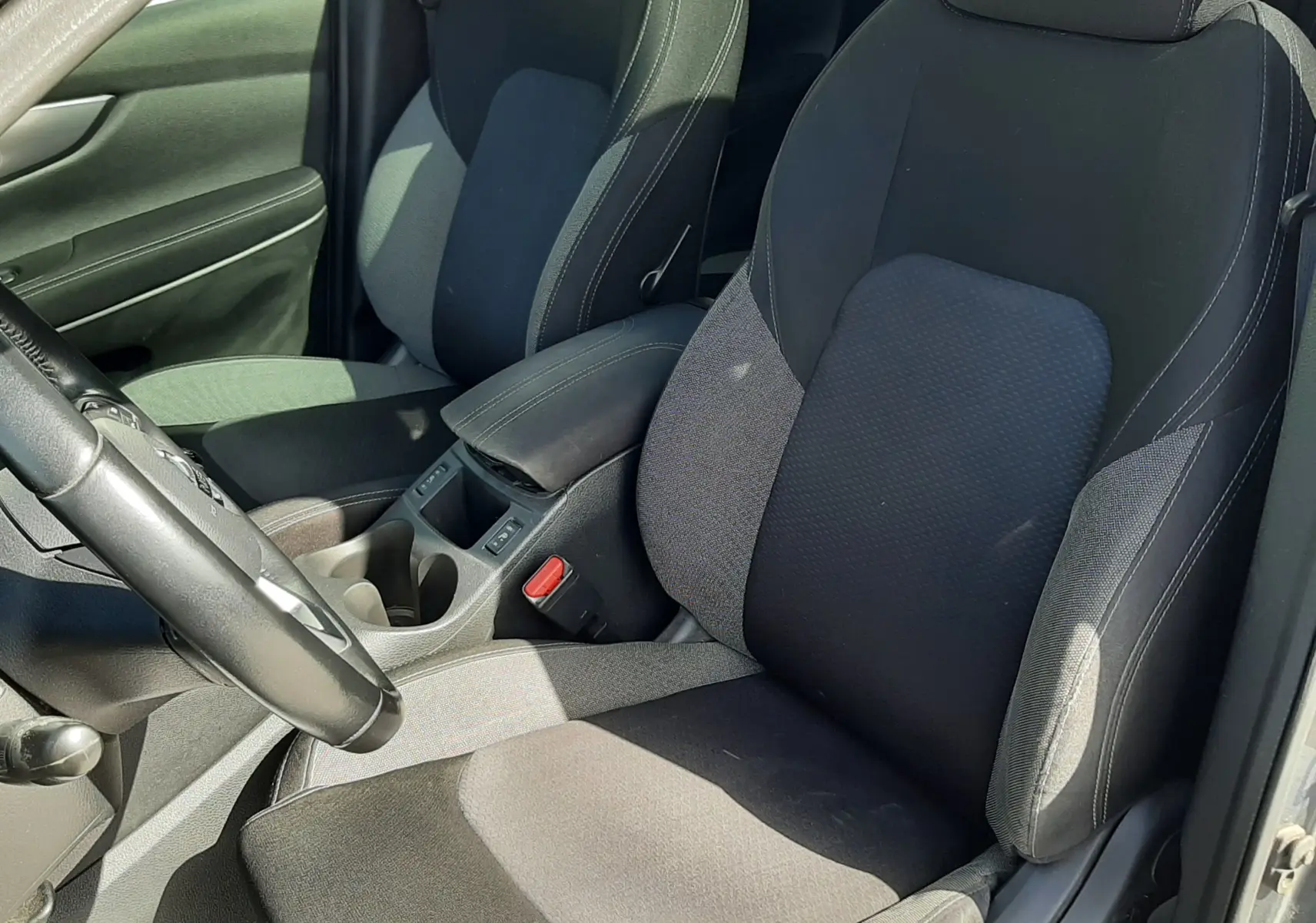 Vue rapprochée de l’intérieur du Nissan Qashqai 2018, sièges avant en tissu gris noir avec accoudoir central.